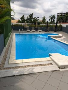 una gran piscina azul con sillas y sombrillas en Premier Executive Apartment - The Ivy, East Legon en Accra