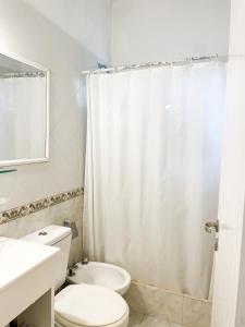 Baño blanco con aseo y lavamanos en Tamanacos Hotel & Spa en Villa Gesell