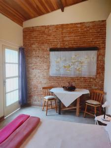 um quarto com uma mesa e cadeiras e uma parede de tijolos em CasaMágica SP em São Paulo
