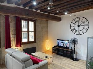 a living room with a couch and a clock on the wall at Appartements chez Delphine et Guillaume au coeur de Semur en Auxois in Semur-en-Auxois