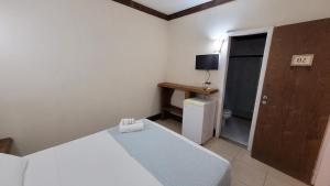 una piccola camera con letto e televisore di Pousada Aquário a Ilha de Boipeba