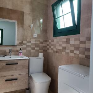 een badkamer met een toilet, een wastafel en een raam bij Apartamento Pocillos Mimosas in Puerto del Carmen