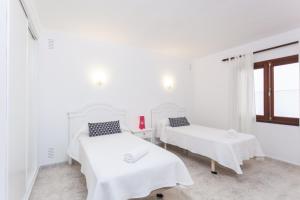 Habitación blanca con 2 camas y ventana en YourHouse Casa Suiza, en Can Picafort