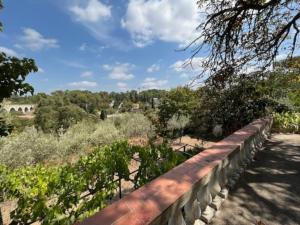 uitzicht op een tuin met een hek en bomen bij La bellevue Nimoise in Nîmes