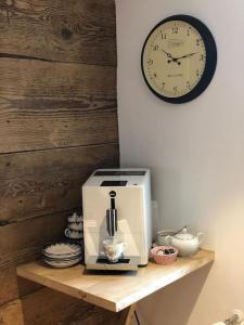 a coffee maker on a wooden shelf with a clock at Wohnung gemütlich mit Stil „la tgea cotschna“ in Pignieu