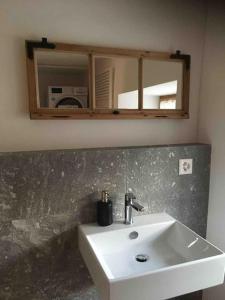 a bathroom with a white sink and a mirror at Wohnung gemütlich mit Stil „la tgea cotschna“ in Pignieu