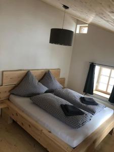 - une chambre avec un lit en bois et des oreillers dans l'établissement Wohnung gemütlich mit Stil „la tgea cotschna“, à Pignieu