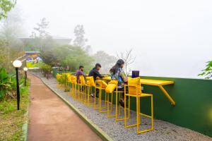 a group of people sitting in yellow chairs on a train at The Hosteller Munnar in Munnar