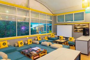 a living room with a blue couch and yellow pillows at The Hosteller Munnar in Munnar