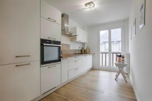 a white kitchen with white cabinets and a television at Les Caravelles - Trois Pièces - Deauville Centre in Deauville