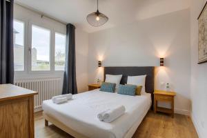 - une chambre avec un grand lit blanc et des oreillers bleus dans l'établissement Les Caravelles - Trois Pièces - Deauville Centre, à Deauville