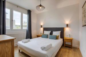 a bedroom with a large white bed with blue pillows at Les Caravelles - Trois Pièces - Deauville Centre in Deauville