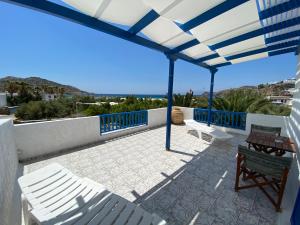 un patio con sillas blancas y una sombrilla azul y blanca en Deep Blue Rooms & Apartments, en Mylopotas