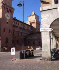 a building with a clock tower and a building with a street sign at Elegante appartamento nel cuore di Ferrara in Ferrara