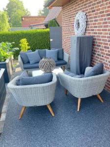 two wicker chairs and two couches on a patio at SchlaWenke- Hier schlafen Sie gut in Herzlake