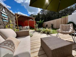 un patio avec des chaises et un parasol sur une terrasse en bois dans l'établissement Maison « Embruns de mer » à 800 m de la mer, à La Pironnière