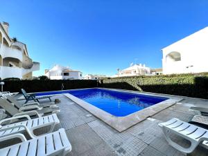 una piscina con tumbonas blancas junto a un edificio en Quarteira Classic 1 With Pool by Homing, en Quarteira