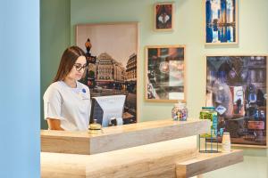 a woman standing at a counter with a laptop at Hôtel Kabanel by Happyculture in Paris