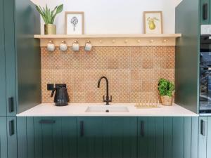 a kitchen with a sink and a tiled wall at 1 Caddaford Barns in Buckfastleigh