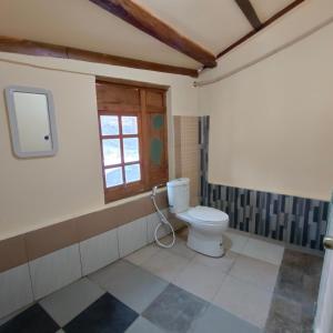 a bathroom with a toilet and a window at Omah Singo Stay and Resto in Bantul