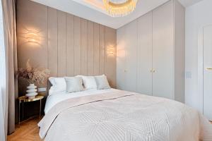 sypialnia z dużym białym łóżkiem i żyrandolem w obiekcie Wyjątkowy Taupe Apartament w centrum Łodzi w Łodzi