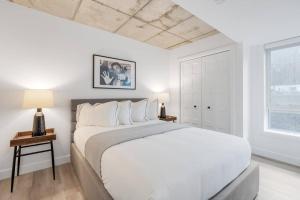 ein weißes Schlafzimmer mit einem großen Bett und einem Fenster in der Unterkunft Initial / Cinéma +Parking / Centre-ville de Québec in Québec