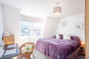 a bedroom with a purple bed and a desk and a window at No 5 Compass - Ilfracombe in Ilfracombe