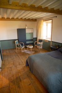 a bedroom with a bed and chairs and a table at Un petit bout du monde in Saint-Georges-en-Couzan