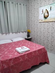 een slaapkamer met een roze bed met een handdoek erop bij Suíte 10 Privativa e Aconchegante in Cuiabá