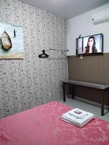 een slaapkamer met een tv aan de muur en een roze tapijt bij Suíte 10 Privativa e Aconchegante in Cuiabá
