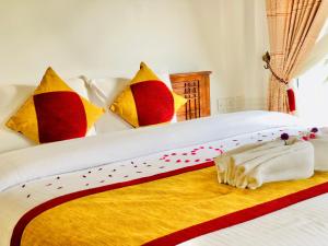 een bed met kleurrijke kussens en een handdoek erop bij Seeming Lodge in Nuwara Eliya