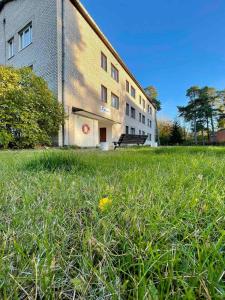 a building with a field of grass in front of it at Laine guesthouse in Narva-Jõesuu