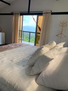 a white bed with pillows and a large window at La Paloma Glamping in Palestina