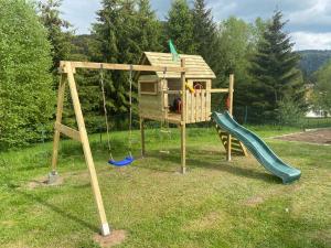 a wooden playground with a slide and a swing at Le Chalet de la Devinière in Xonrupt-Longemer