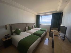 a hotel room with two beds and a window at Hotel Azur in Casablanca