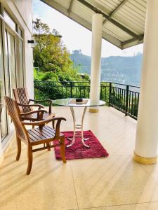 een patio met een tafel en 2 stoelen op een balkon bij Seeming Lodge in Nuwara Eliya