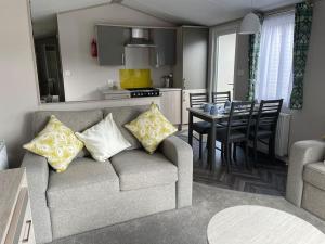 a living room and kitchen with a couch and a table at The Warrens - 2 bed caravan for 4 & private hot tub in Swarland +20 photos