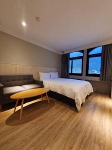 a bedroom with a bed and a couch and a table at Yoshi Hotel in Tainan