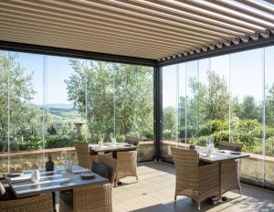 uma sala de jantar com mesas e cadeiras e grandes janelas de vidro em Locanda Le Piazze em Castellina in Chianti