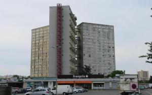 um grande edifício com carros estacionados num parque de estacionamento em Charmant F2 de 30m2 moin cher à 25 min de Paris jusqu'à 5 personnes em Le Mée-sur-Seine