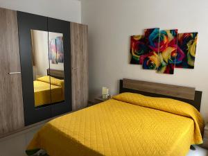 a bedroom with a yellow bed and two paintings on the wall at Claire's Court in Marsaxlokk