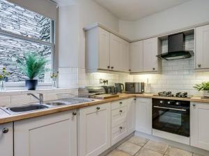 eine Küche mit weißen Schränken, einem Waschbecken und einem Fenster in der Unterkunft Gorgeous cottage in Bowness in Bowness-on-Windermere