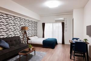 ESLEAD HOTEL Namba Ebisu West في أوساكا: غرفة بسرير واريكة وطاولة