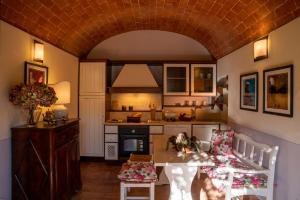 eine Küche mit einem Tisch und Stühlen sowie eine Küche mit einem Herd in der Unterkunft Borgo San Benedetto in Montaione