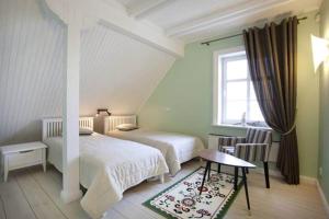 a bedroom with two beds and a table and a window at Vila Pervalka in Pervalka