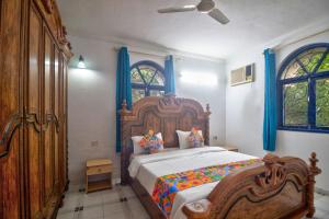 a bedroom with a large wooden bed with blue curtains at Hilltop 4BHK Villa with Private Pool Near Candolim in Old Goa