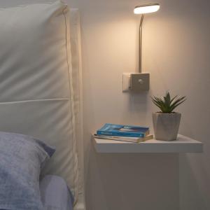 a bed with a nightstand with a plant and a lamp at La Casa di Andre in Sanremo