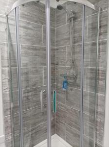 a shower in a bathroom with a wooden wall at Victorian Renovation Room 4 in Liverpool