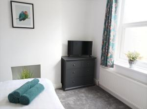 a bedroom with a bed with a television and a dresser at Victorian Renovation Room 4 in Liverpool
