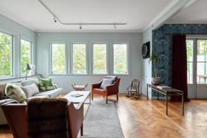 ein Wohnzimmer mit einem Sofa, Stühlen und Fenstern in der Unterkunft Fantastic 4 bedroom home in Bromma with everything in Stockholm